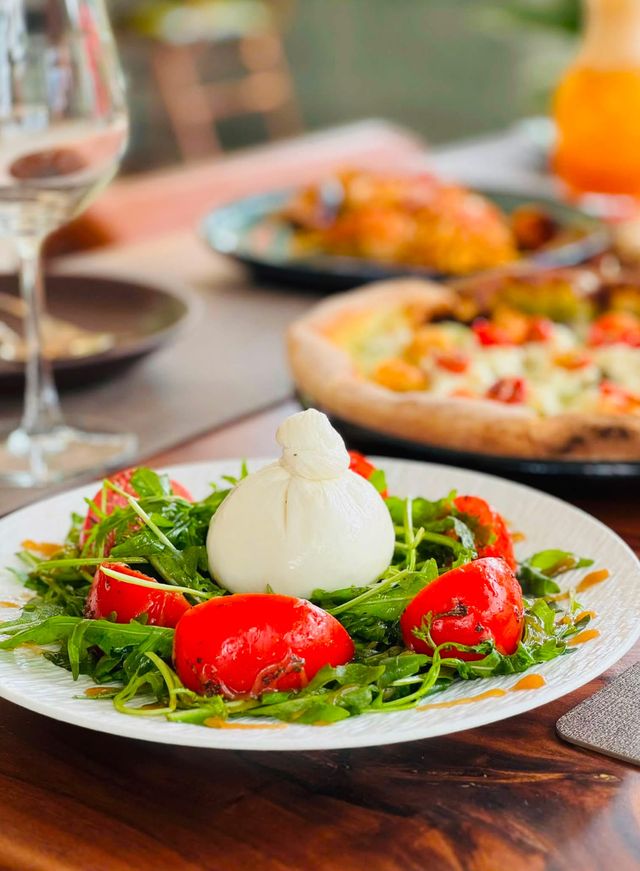 A burrata on a bed of rocket with roasted tomatoes