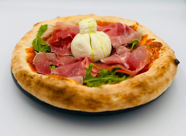 Pizza topped with prosciutto, rocket and a whole burrata