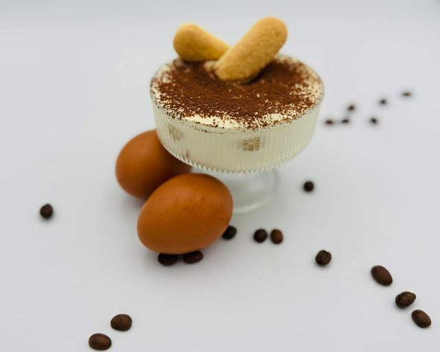 Tiramisu in a glass topped with cocoa and two ladyfingers